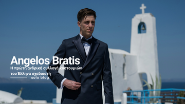 Άνδρας φορά navy επίσημο κοστούμι Angelos Bratis με σατέν πέτο και παπιγιόν, σε εξωτερικό ελληνικό νησιώτικο σκηνικό με λευκή εκκλησία.