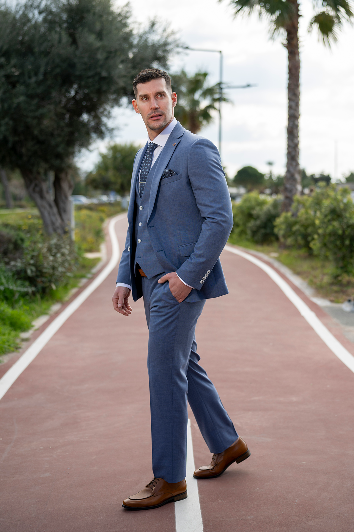 Ανδρικό 3-piece κοστούμι Makis Tselios σε γκρι σιέλ τόνους με casual διάθεση  από εξωτερική φωτογράφιση του SOLO